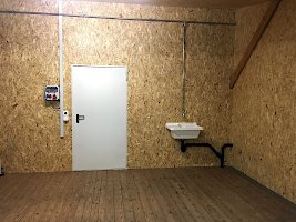 Innenansicht des Raums auf die Türe, Stromkasten und Waschbecken.